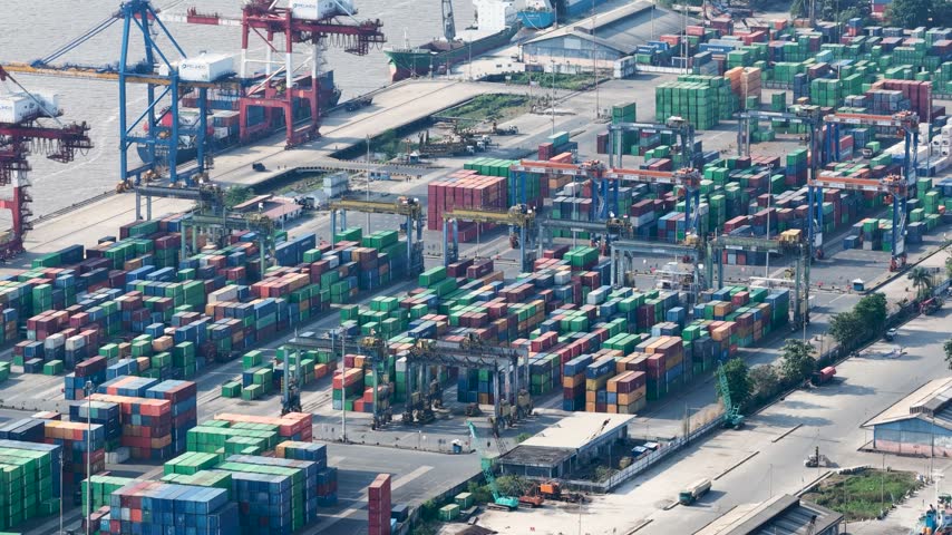 Shipping containers stacked in an active harbor port area during a sunny afternoon