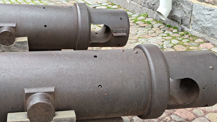 A pair of old cannons sitting on a stone ground.