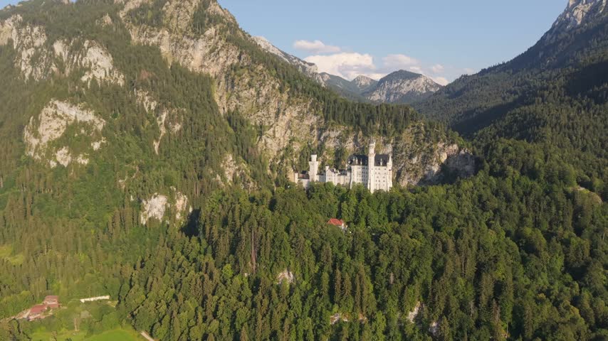 Majestic aerial view of the famous Neuschwanstein Castle. A fairytale palace perched on a rugged hill surrounded by a dense green forest