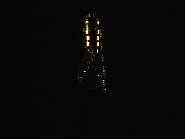 Medium shot of tungsten light bulb with soft ambient light being turned on 