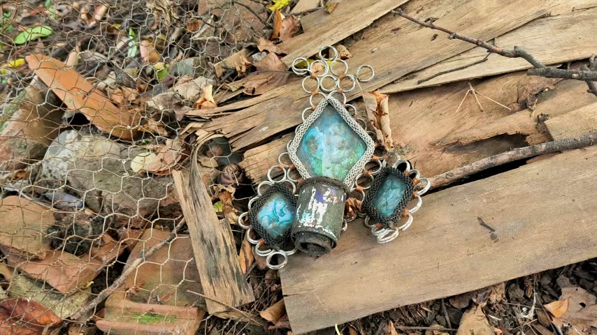 An old metal orthodox vigil lamp (candela) holder with blue glass inserts resting on weathered wooden boards outdoors in rural Romania.