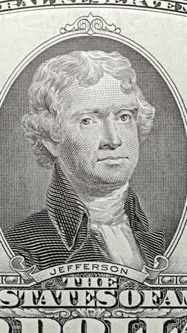 Thomas Jefferson bill under green security scan. Green scan light moves across Thomas Jefferson bill, making banknote glow. This anti counterfeit effect reveals portrait layers as image shifts from top to bottom.