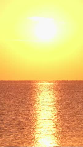 Sunset glowing brightly over the water, creating reflections on the surface. The warm colors dominate the scene, showcasing nature