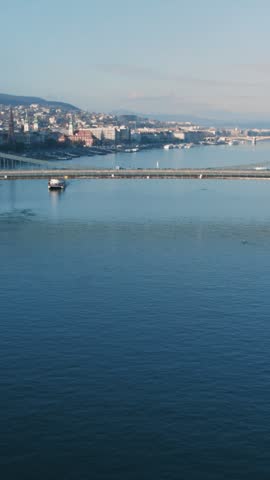 Aerial view of the Szechenyi Chain Bridge spanning the Danube River in Budapest. The Hungarian Parliament Building and cityscape are visible in the background.