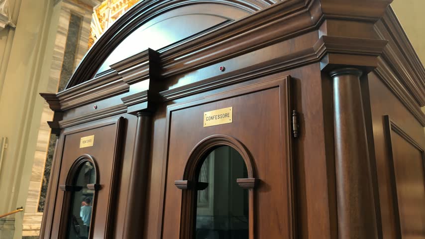Traditional wooden confessional booth inside Catholic church, religious architecture close-up.