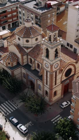 High-angle aerial footage captures a historic Spanish church and surrounding town buildings during daytime.