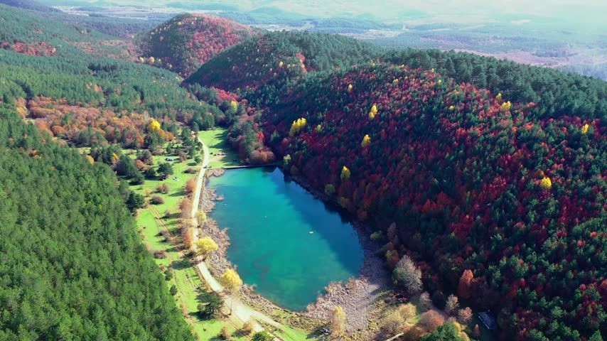 Şirinyazı Pond in Mengen, Bolu, Turkey surrounded by dense forest and colorful autumn foliage across hills and a rural landscape
