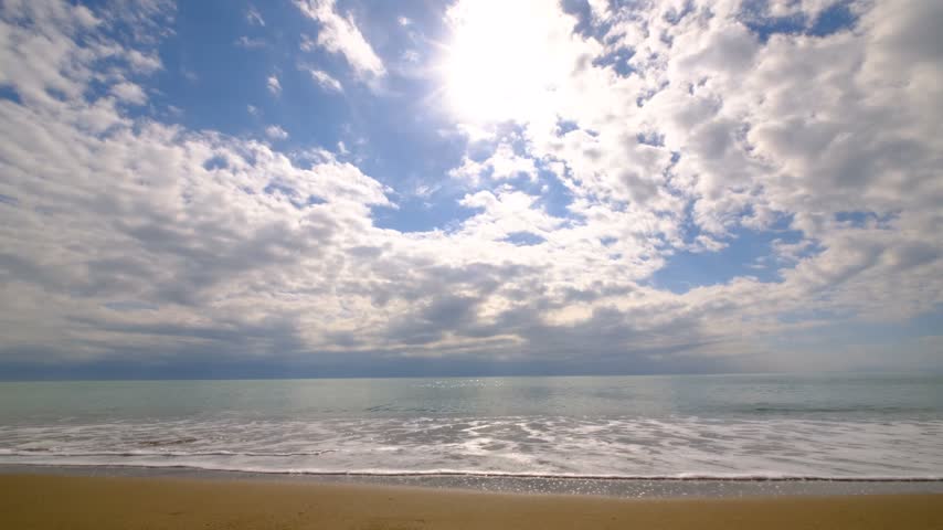 Tropical Beach with Sunlight and Partly Cloudy Sky. Sunny Beach and Sea Under a Partly Cloudy Sky. Sunny Coastal Landscape with Blue Sea and Clouds.