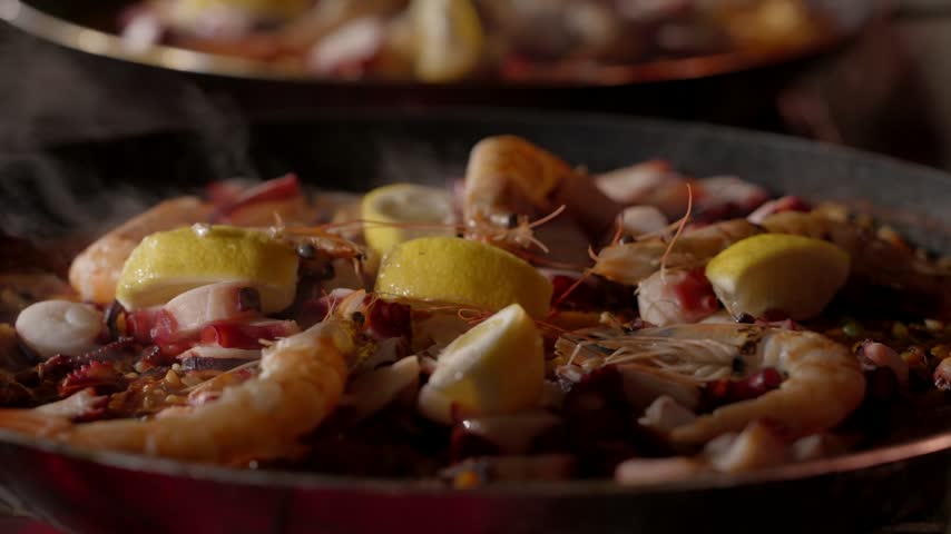 Seafood paella in a paella pan with prawns octopus squid mussels lemon wedges and saffron rice