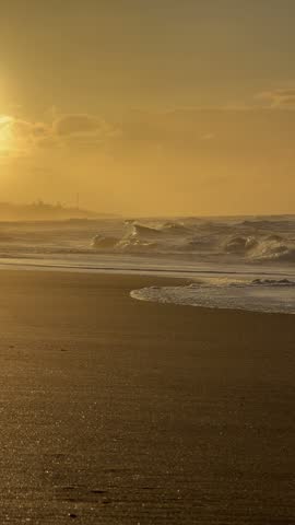 Golden sunrise over the Atlantic Ocean with waves washing onto a sandy beach, Algarve, Portugal
