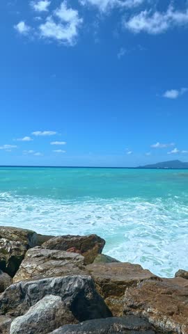 Waves breaking on rocky shoreline with distant island.
