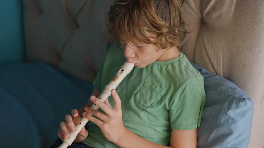 A little boy learns to play the flute at home, practicing with focus and enthusiasm in a cozy, warm setting. A charming scene of early musical exploration, creativity, and childhood growth.