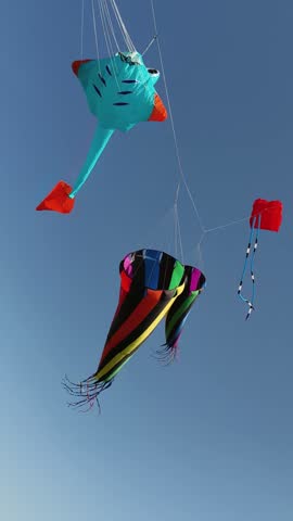 Giant colorful show kites with spinning windsock cones in blue sky
