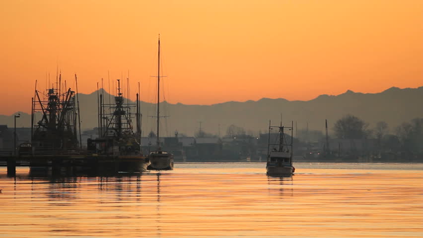 Steveston Harbor Commercial Fish Boat at Dawn. A fish boat departs Steveston Harbor on the Fraser River in British Columbia, Canada at sunrise.