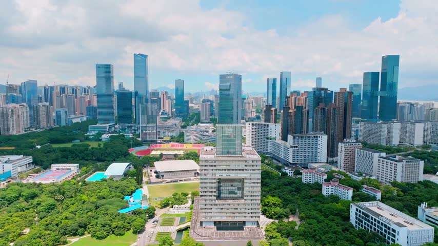 Aerial view of university buildings and bright blue sports courts in Shenzhen, Guangdong, China. The scene features Shenzhen University. Relevant to higher education and campus planning.