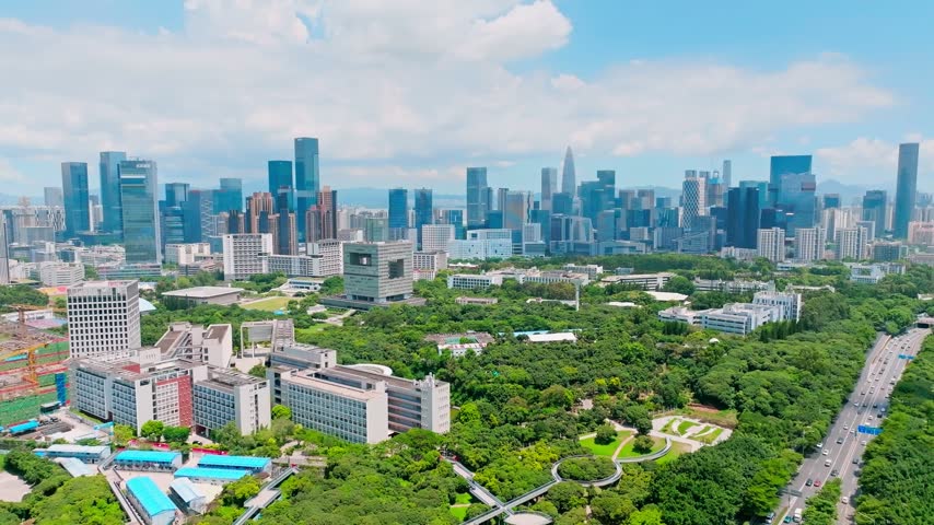 Aerial view of leafy campus bordered by a broad city road in Shenzhen, Guangdong, China. The scene features Shenzhen University. Relevant to higher education and campus planning.