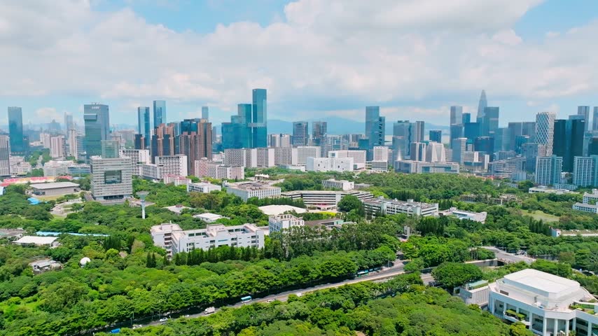 Aerial view of low campus buildings against distant office towers in Shenzhen, Guangdong, China. The scene features Shenzhen University. Relevant to higher education and campus planning.