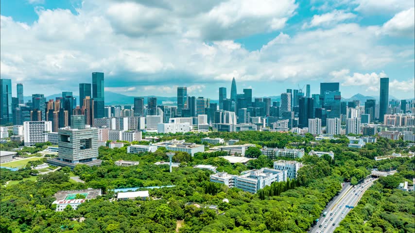 Aerial view of cloud filled sky over a tree covered campus in Shenzhen, Guangdong, China. The scene features Shenzhen University. Time-lapse footage. Relevant to higher education and campus planning.