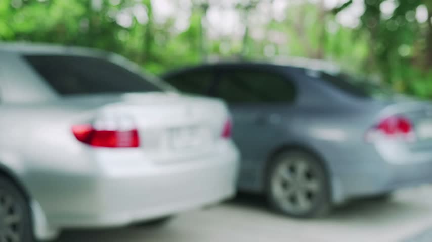 Close up of man holding car keys. Gentleman in suit presents keys for vehicle. Outdoor parking lot with cars.