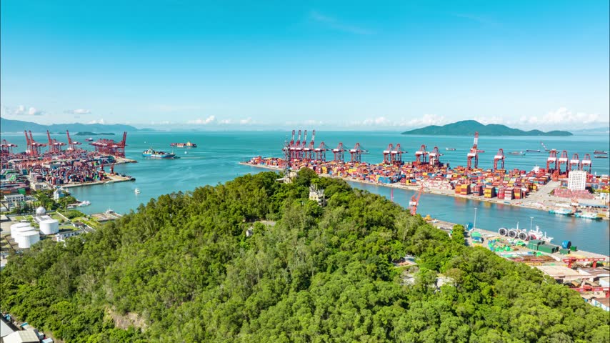 Aerial view of wooded hill between industrial harbor terminals in Shenzhen, Guangdong, China. The scene features Shekou Port. Time-lapse footage. Relevant to maritime logistics and trade infrastructure.