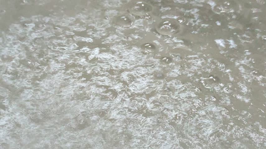 A hot sulfur spring bubbling and emitting steam like boiling water in a geothermal field.