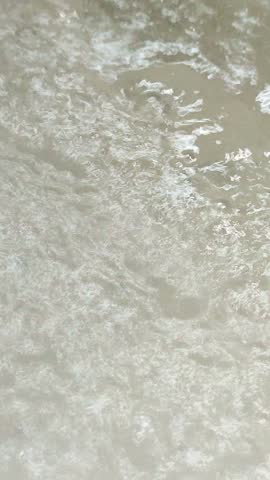 A hot sulfur spring bubbling and emitting steam like boiling water in a geothermal field.