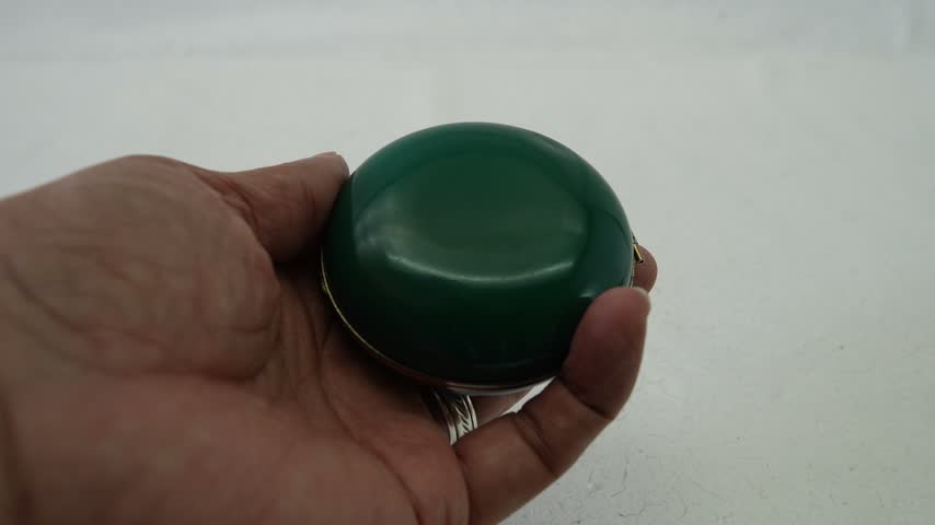 Hand holding a green vintage pocket watch