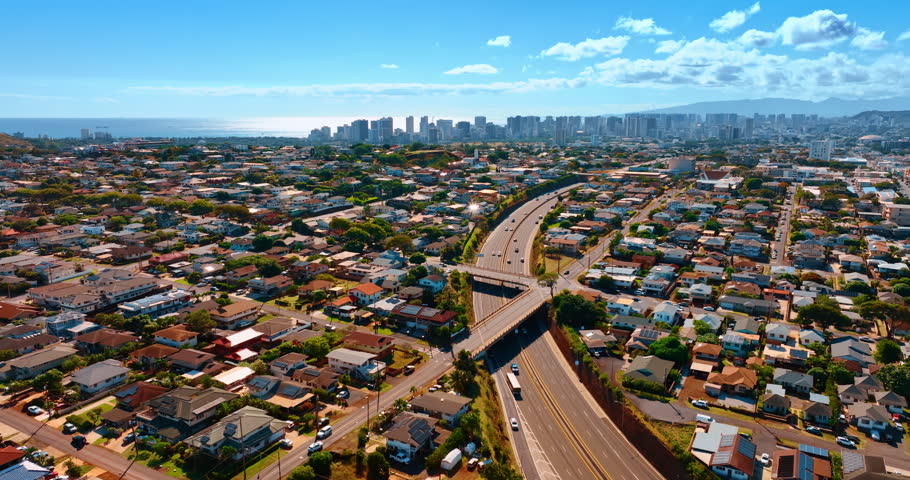 Low-rise scenery of Honolulu crossed by the highways. High-rise skyline of downtown at backdrop. Hawaii, USA. Aerial view.