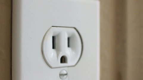 PLUG INSERTED INTO WALL SOCKET.

An extreme close-up of a plug being inserted into a wall socket.