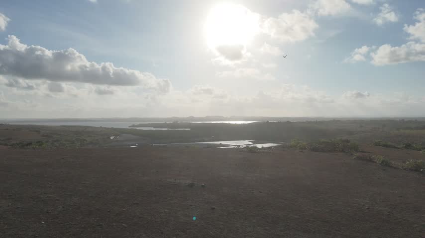 Aerial view of coastal landscape with reflecting ponds under bright sunny sky