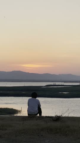 Person Sitting by a Lake at Sunset