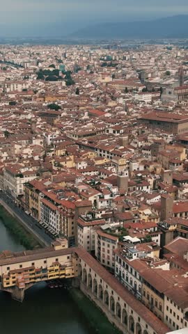 High-angle aerial drone shot panning across the historic cityscape of Florence, revealing iconic landmarks including Ponte Vecchio and Florence Cathedral.