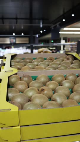 Vertical screen fresh kiwi fruits fill cardboard produce boxes in a grocery store showing ripe tropical food ready for retail sale healthy eating and daily food shopping
