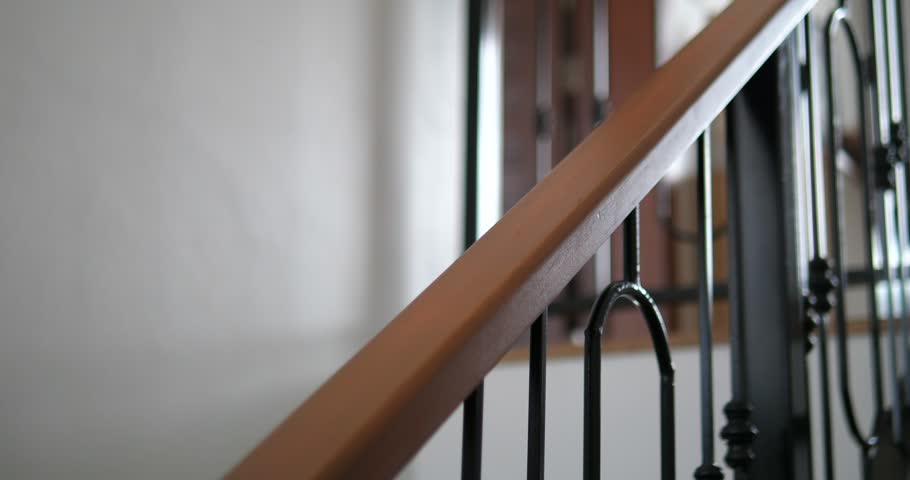 Close up of wooden handrail with wrought iron balusters on staircase