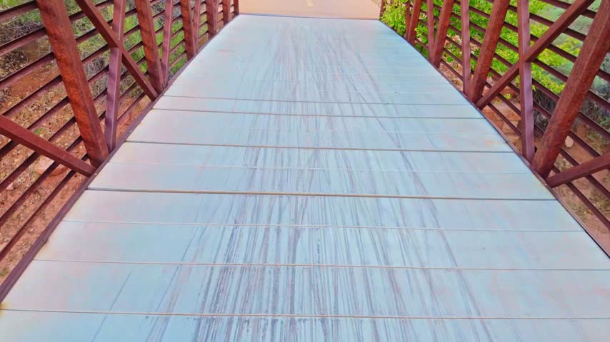 A bridge crosses the hiking trail with the colorful rock formations of Zion National Park rising behind