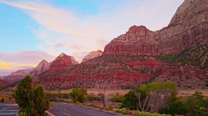 Golden sunset light highlights the red cliffs over desert cactus landscape of Zion National Park