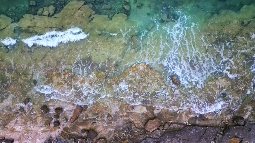 Aerial view of the coastline where waves crash against rocky shores. The scenic seaside showcases nature