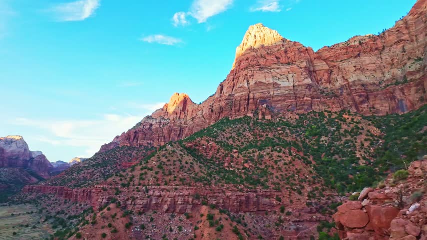 Golden sunset light glows over the mountains as seen from the top of the Watchman Trail in Zion National Park