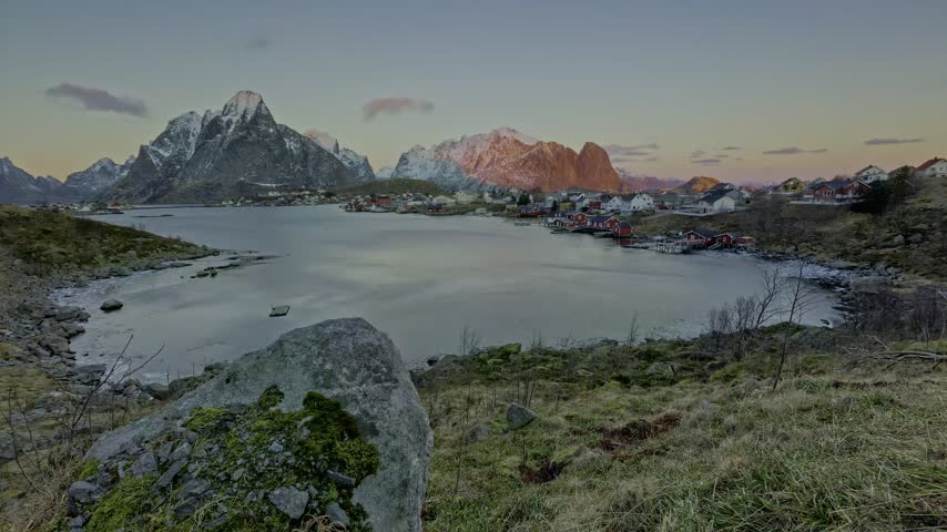 Vibrant sunset over a tranquil glacial lake framed by dramatic mountain peaks.