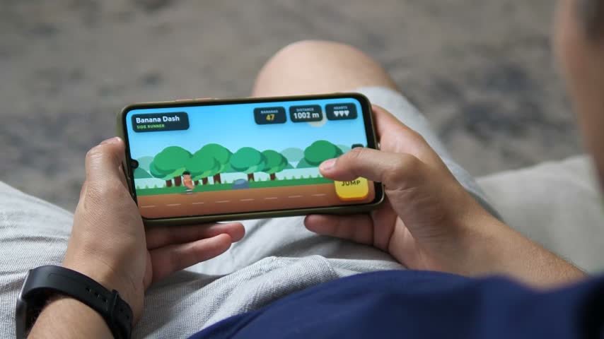 Person plays a colorful side-scrolling mobile game on a smartphone, highlighting casual gaming, touchscreen interaction, digital entertainment, and everyday leisure at home.