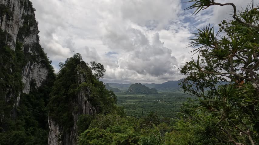 This elevated perspective captures the rugged beauty of tropical limestone mountains, dense jungle, and distant valleys in Southern Thailand.