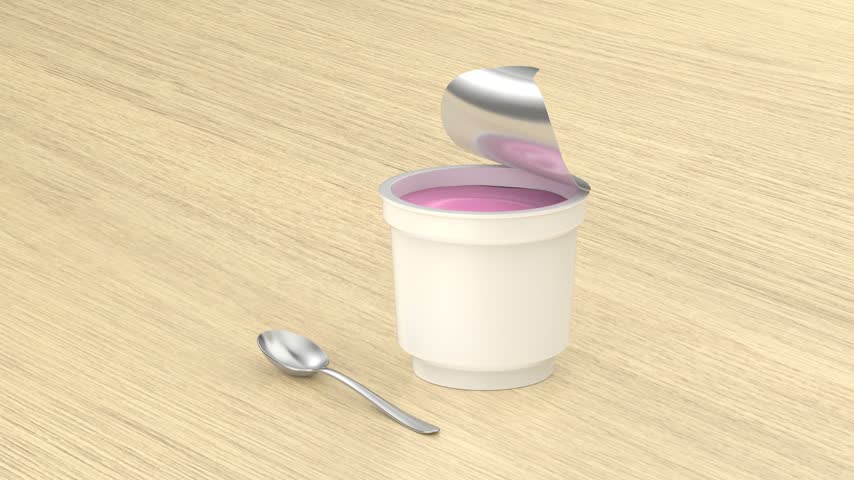 Strawberry yogurt container and silver spoon on wooden table