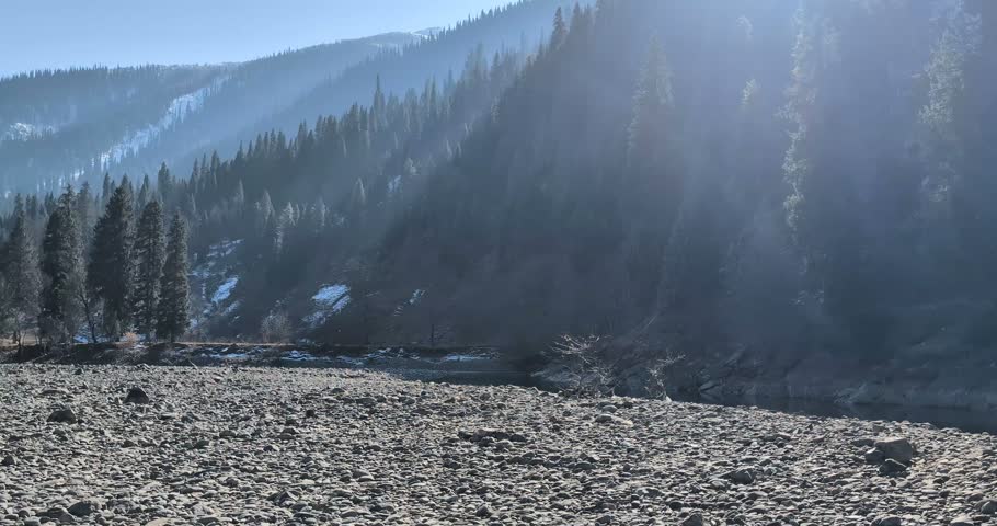 Winter mountain landscape with rocky riverbank under clear skies