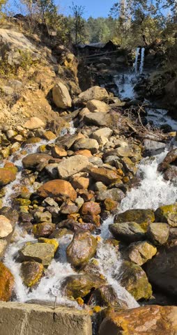 Small mountain stream flowing over rocks in a forest landscape with natural daylight