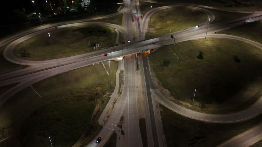 Static night drone aerial over a cloverleaf highway interchange overpass with vehicle lights and road illumination in Winnipeg, Manitoba, Canada.