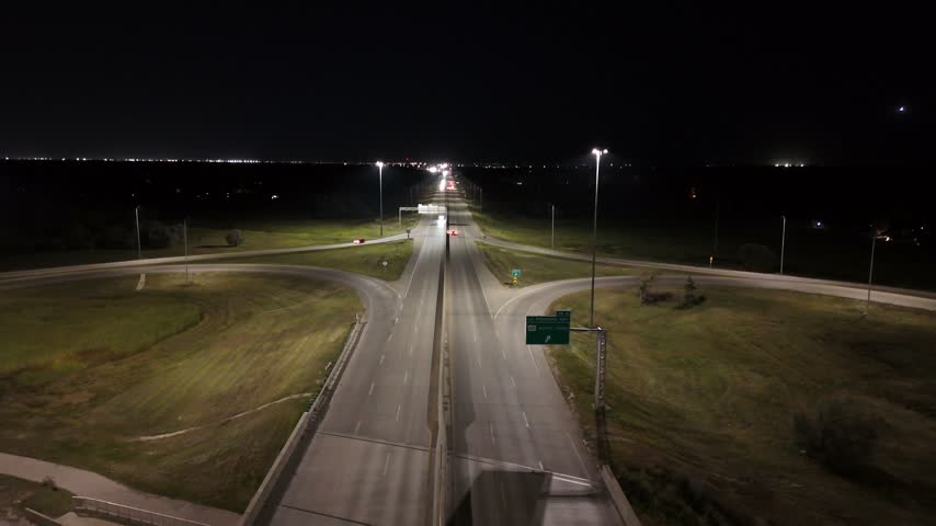 Night drone aerial ascending while facing east over the South Perimeter Highway and Pembina Highway cloverleaf overpass in Winnipeg, Manitoba, Canada.