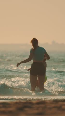 Woman walks in shallow water at the beach during sunset near the ocean