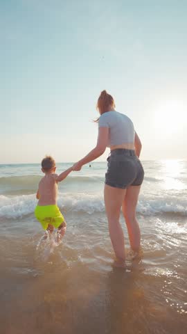 Child and parent play in the sea on a sunny day at the beach near the shore