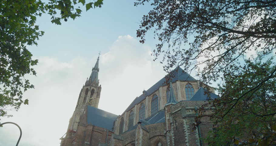 Netherlands, Europe historic church cathedral Gothic architecture blue roof spire tall tower brick facade sky clouds trees surrounding view