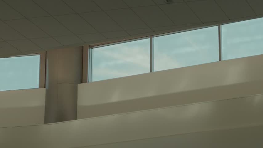 Right-to-left pan across high interior windows beneath a bright daytime sky.